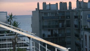 Ein mehrstöckiges Gebäude mit Balkonen, Blick auf das Meer und einem Sonnenuntergangshimmel.