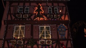 En bygning med mange vinduer, hvoraf nogle er pyntet med julelys og dekorationer.