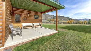 Une cabane en rondins avec une véranda, deux bancs et une antenne parabolique.