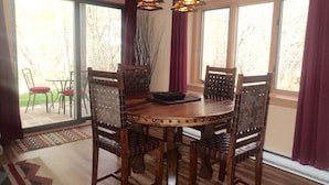 Un comedor con una mesa redonda de madera, cuatro sillas y dos lámparas colgantes.