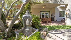 A stone Buddha statue in a garden with a patio area, outdoor seating, and a covered entrance. - Buddha Estate, Pool , Spa, Sauna, Game Room (Las Vegas)