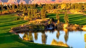 A golf course with a pond, a flag, and mountains in the background. - Buddha Estate, Pool , Spa, Sauna, Game Room (Las Vegas)