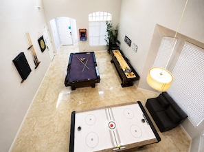 Una habitación con mesa de billar, mesa de futbolín y mesa de billares.