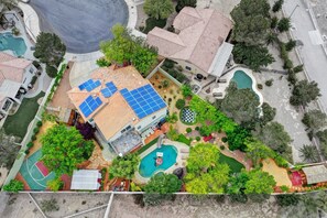 Una propiedad residencial con piscina, paneles solares y cancha de baloncesto.