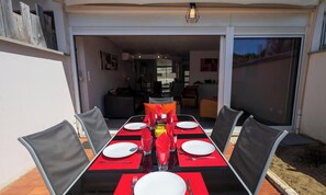 Een eettafel gedekt voor vier personen, met rode placemats, witte borden en heldere glazen.