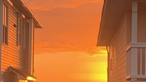 A coastal scene with wooden houses and a boat on the water during sunset.