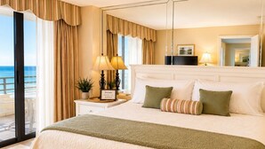 Camera d'albergo con un letto grande, un comodino con una lampada, vista sul mare e un balcone.