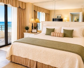 A hotel room with a large bed, a nightstand with a lamp, a view of the sea, and a balcony. - Direct Oceanfront Views, Beach Access, New Pool and Views Galore! XL Balcony (Daytona Beach Shores)