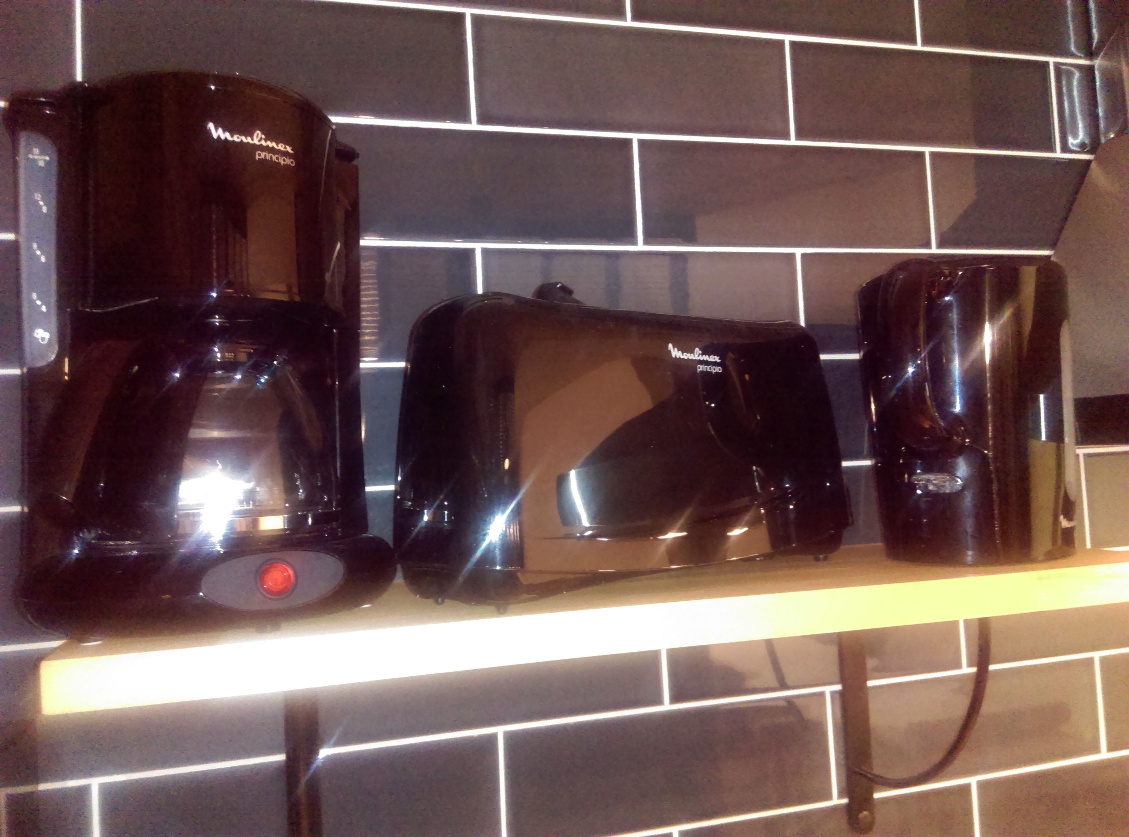 Una encimera de cocina con tres cafeteras negras.