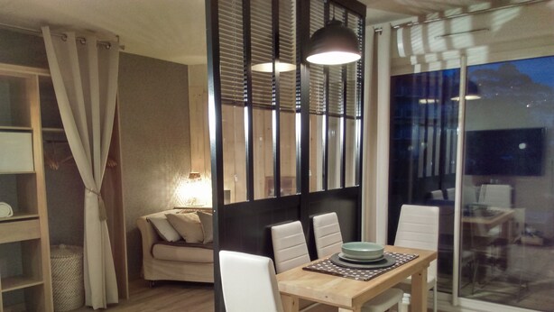 A dining area with a wooden table and white chairs, a sofa, and a glass door leading outside. - very nice studio with real quiet bed at 1400m. from the center and the beaches (Menton)