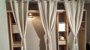 A walk-in closet with beige curtains tied at the top, wooden shelves, and a small white shelf with a decorative item. - very nice studio with real quiet bed at 1400m. from the center and the beaches (Menton)