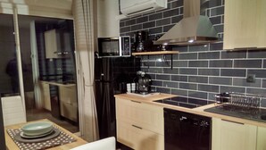 A modern kitchen with a black tiled backsplash, stainless steel appliances, and wooden cabinets. - very nice studio with real quiet bed at 1400m. from the center and the beaches (Menton)