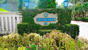 A sign for "Ocean Club" with a number 31, surrounded by lush greenery and flowering plants.