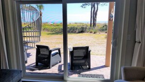 A sliding glass door leading to an outdoor patio with two wicker chairs and a metal gate.
