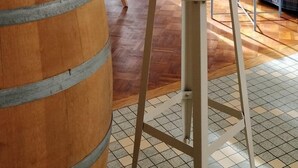 Une pièce comprenant un tonneau en bois, une table à manger avec des chaises, un canapé, une petite table avec un verre et un téléviseur posé sur un meuble.