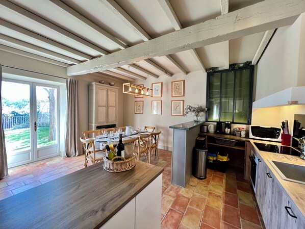 Une cuisine dotée d’un plan de travail en bois, d’un coin repas avec des chaises, d’un meuble de rangement et d’une vue sur l’extérieur.