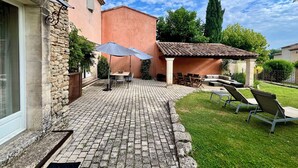 Eine Terrasse mit Backsteinpflaster, Gartenmöbeln und einer Pergola.