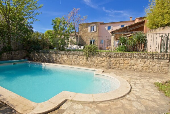 Una piscina con un muro de piedra y un edificio de piedra al fondo.