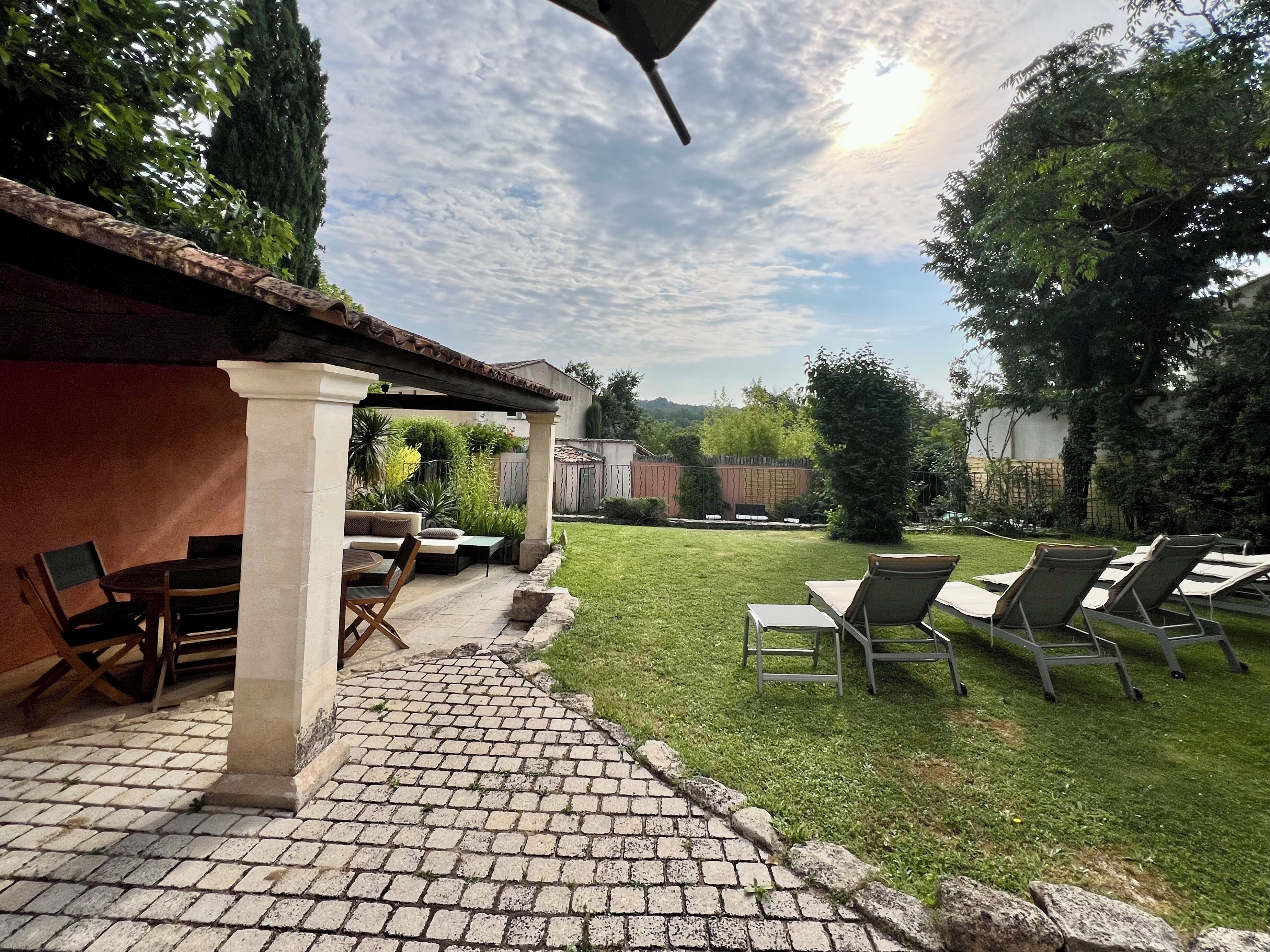 A patio area with a brick pathway leading to a seating area with chairs and a table.
