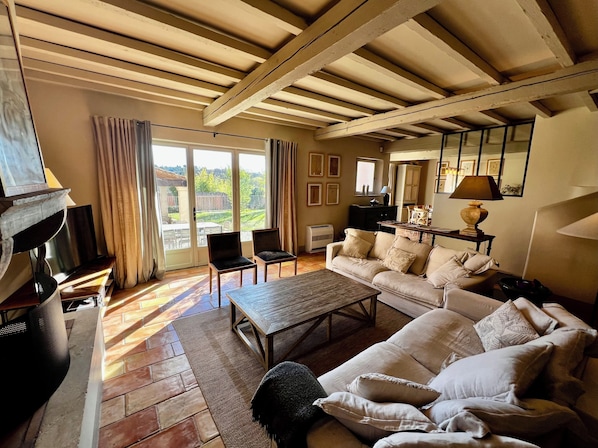 A living room with a sofa, chairs, a coffee table, a fireplace, and a view through a sliding glass door.