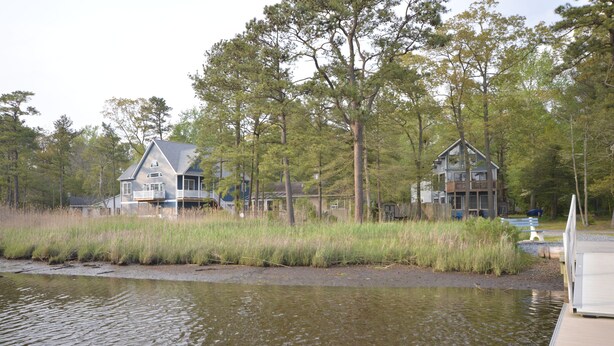 A waterfront property with two houses, a dock, and a bench. - Waterfront Tranquil Escape-Single Family/Gated Community/Pool/Tennis Courts  (Lewes)