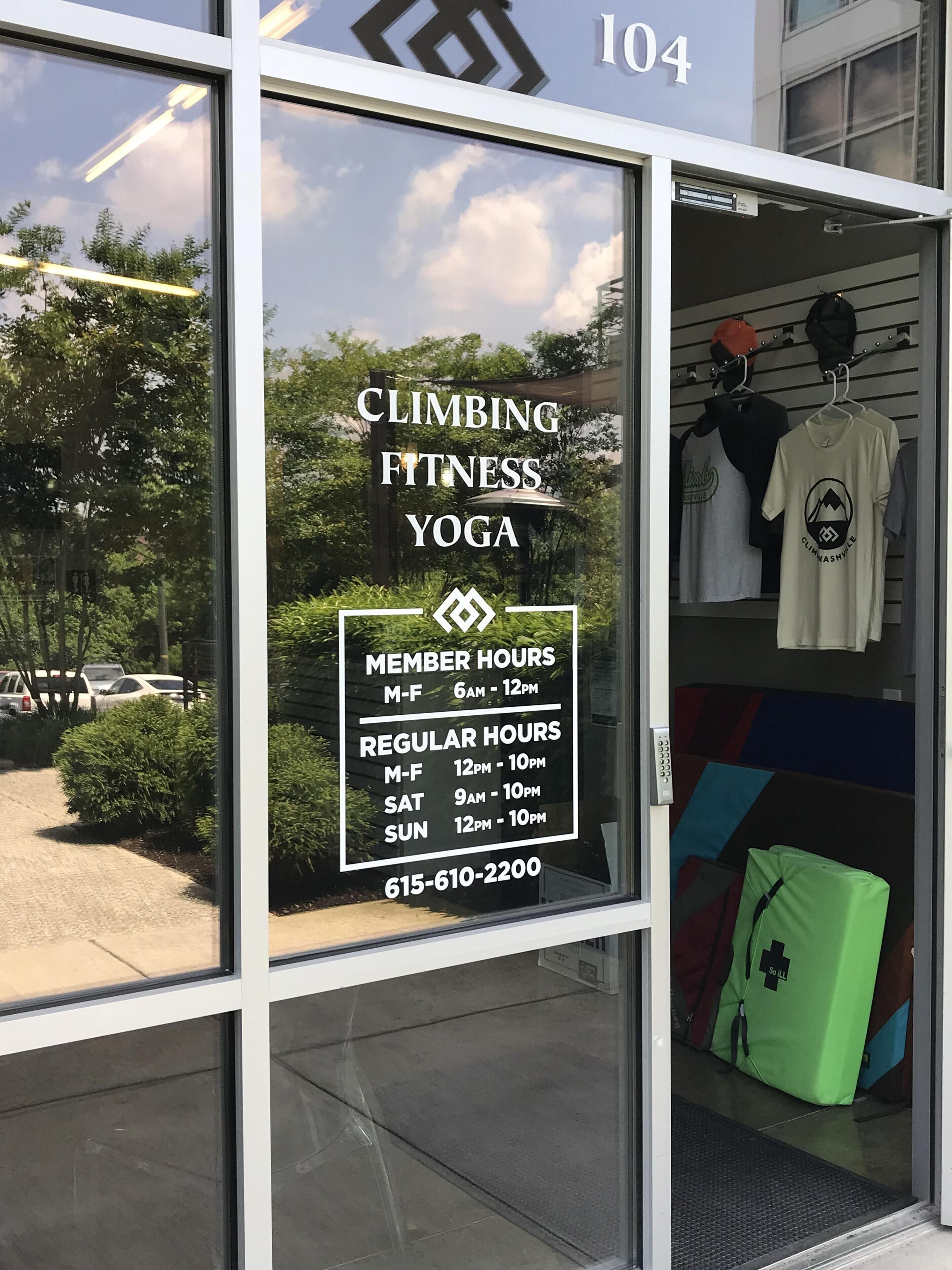 A Climbing Fitness Yoga store with a glass window displaying membership hours and a phone number.