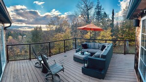 A deck with a gray sofa, two chairs, and a red umbrella. - BIG Family & Multi-Family Cottage with Incredible View, Hot Tub & Sauna (Dunchurch)