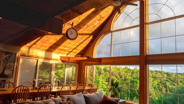 A cozy interior with a wooden ceiling, large windows, a dining area, and a sofa. - BIG Family & Multi-Family Cottage with Incredible View, Hot Tub & Sauna (Dunchurch)