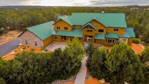 Un grand chalet à plusieurs étages, doté d’un toit végétalisé et entouré d’une forêt dense.
