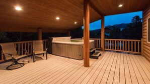 Une terrasse en bois avec un jacuzzi, des chaises longues et une rambarde en bois.