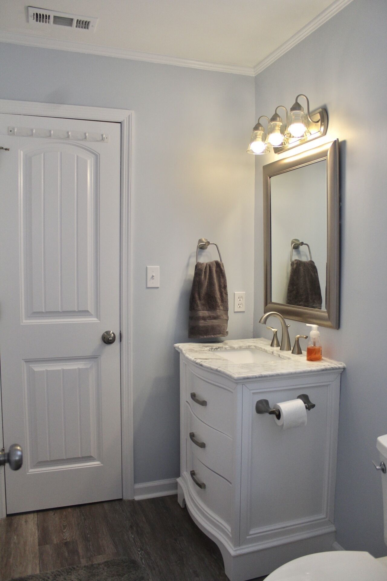 A bathroom with a white vanity, a mirror, a towel rack, and a toilet.