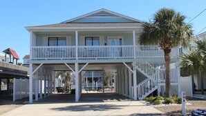 A two-story house with a balcony and a covered porch area.