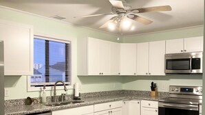 A modern kitchen with white cabinets, a stainless steel dishwasher, a microwave, and an oven.