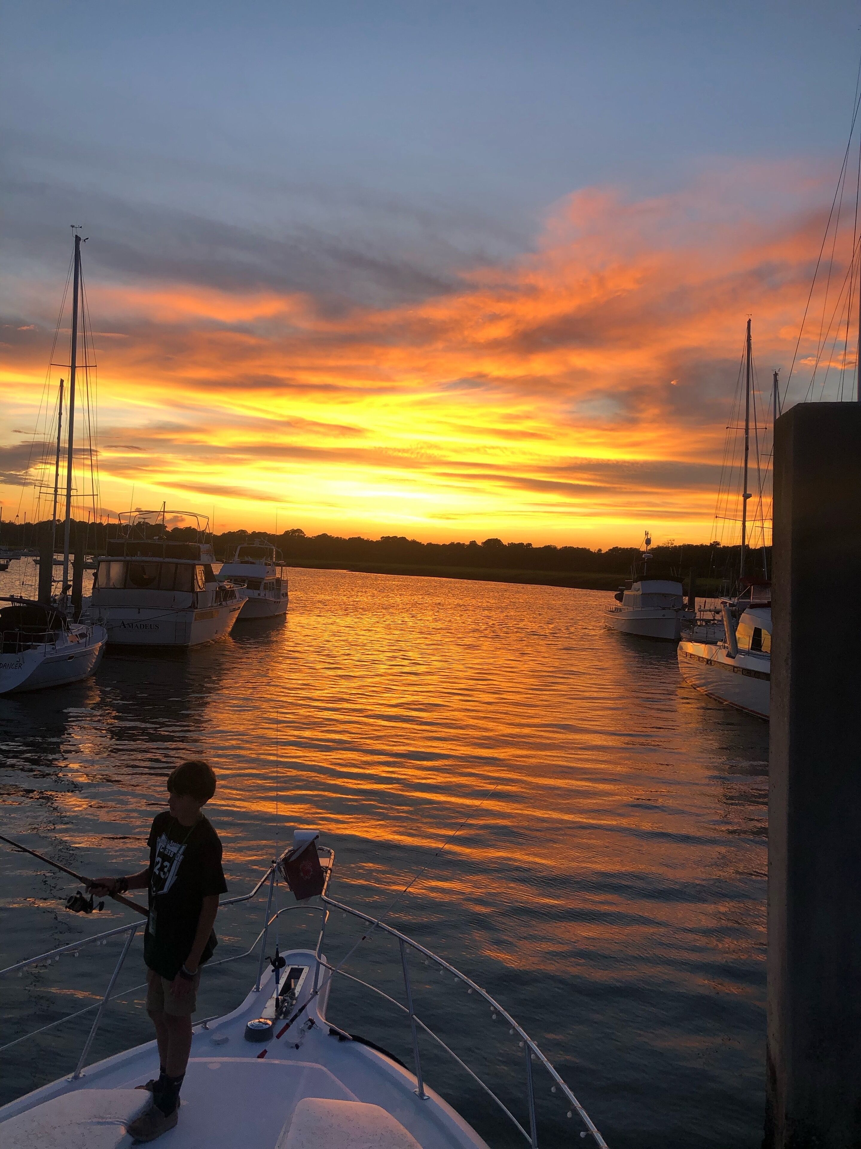 Vista del atardecer desde un barco, con varios otros barcos amarrados cerca.