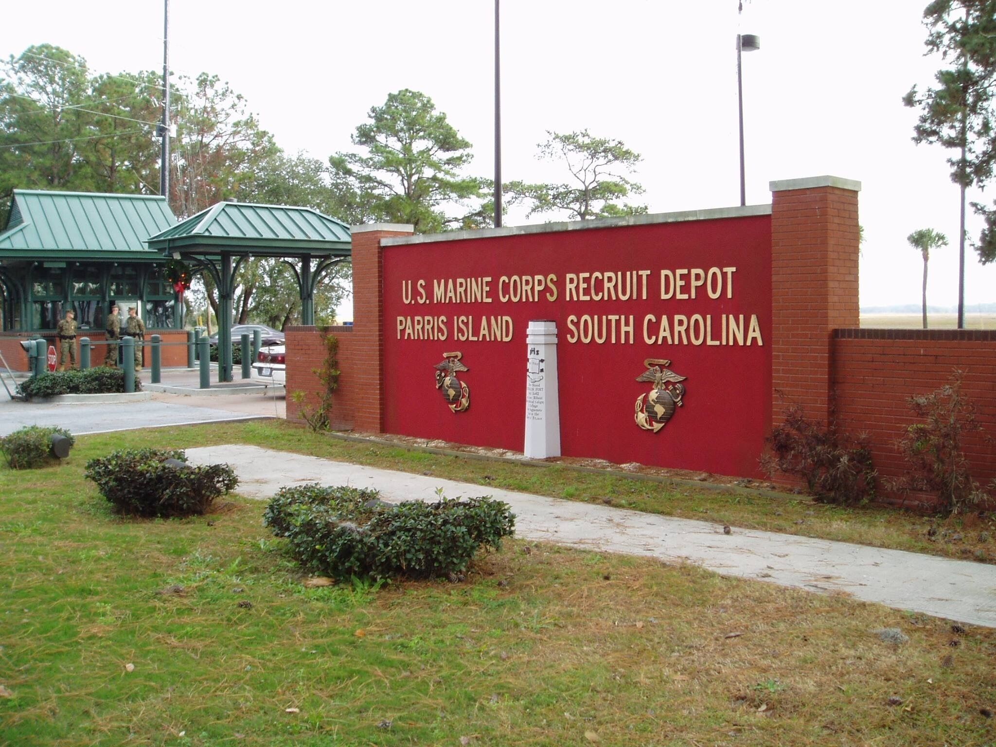 Letrero del Centro de Entrenamiento de Reclutas del Cuerpo de Marines de los Estados Unidos, con un muro de ladrillo y techo verde.