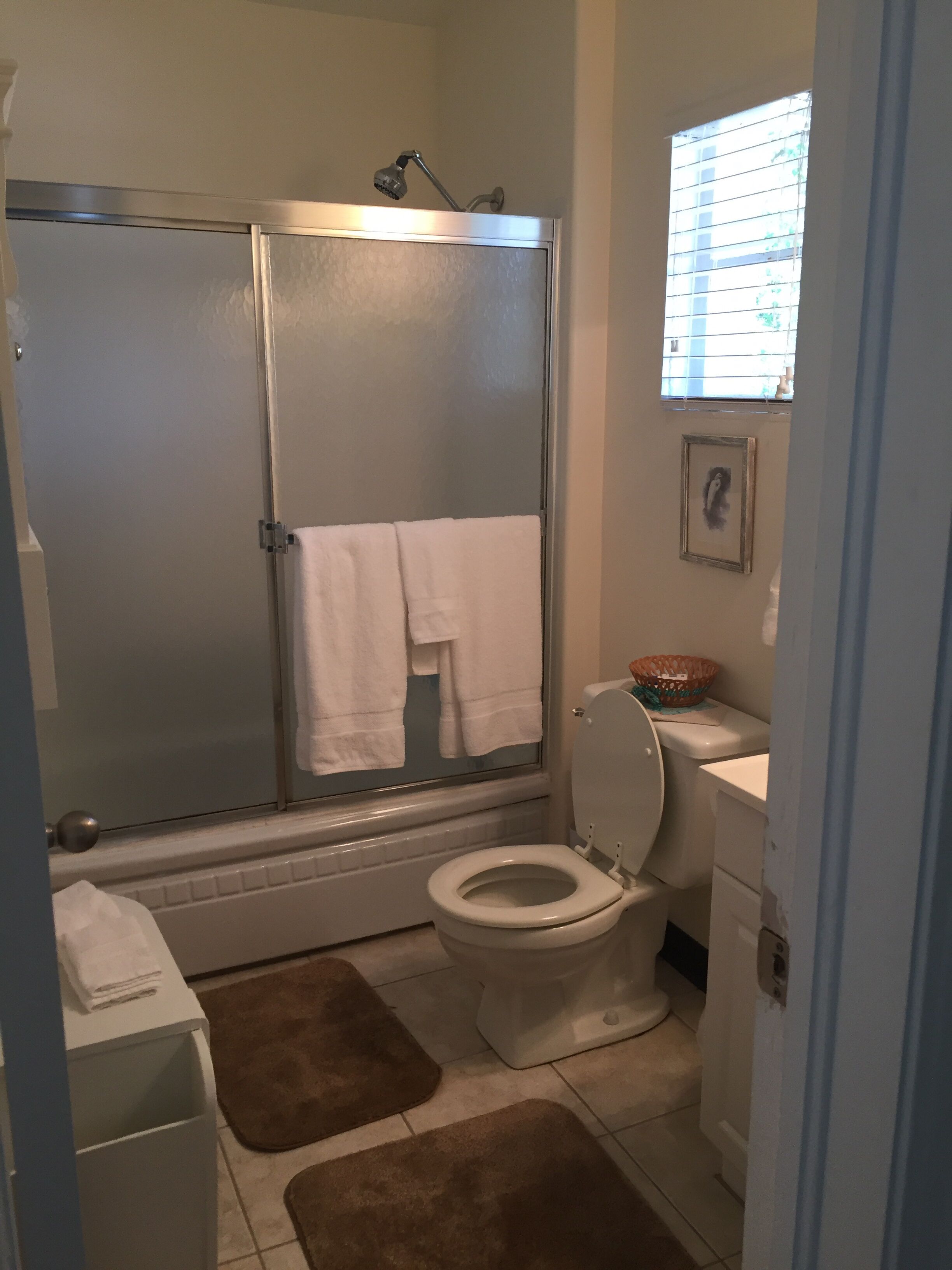 A bathroom with a shower enclosure, toilet, and a small window.