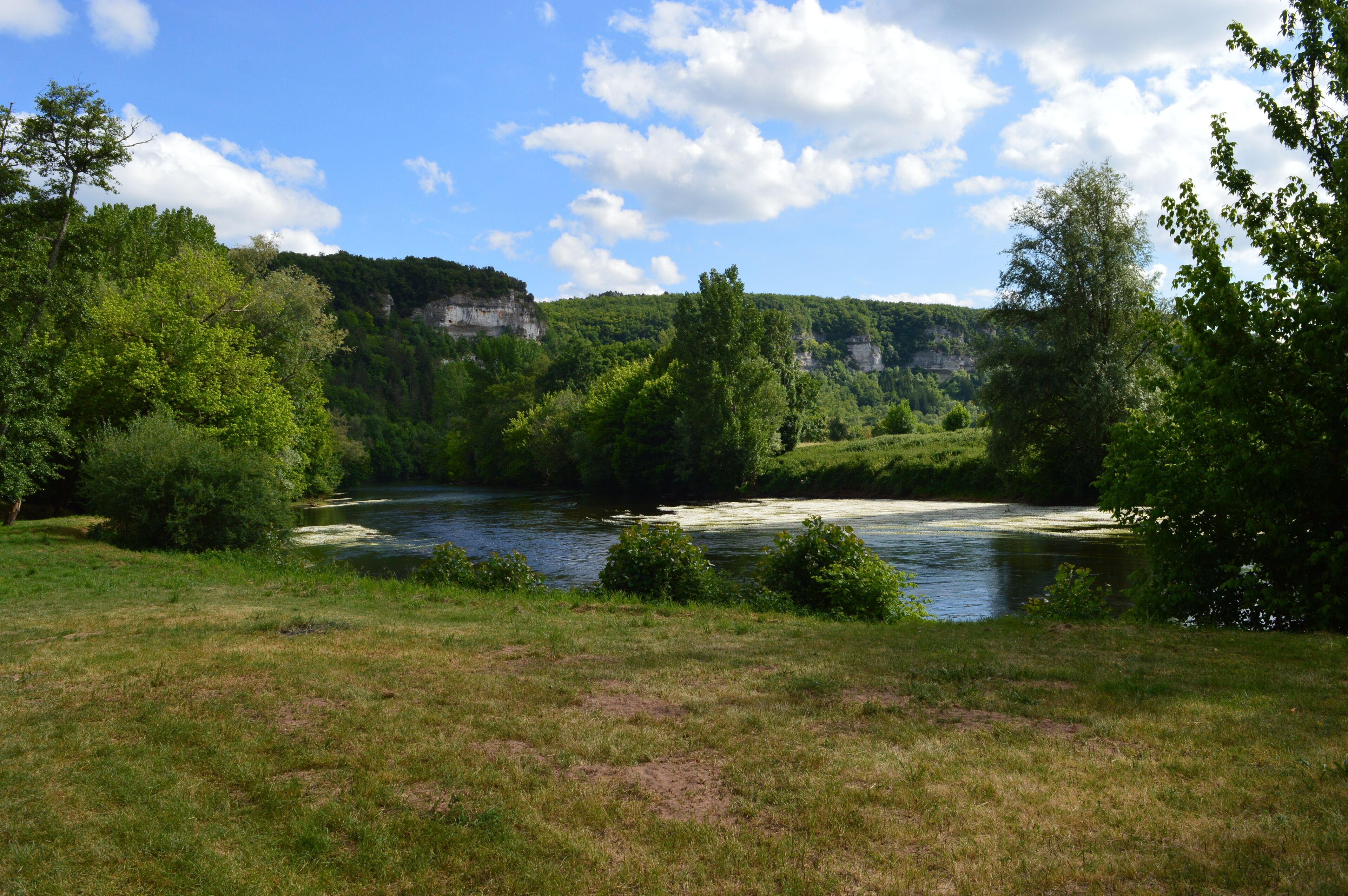 Une rivière bordée d’une végétation luxuriante et de falaises.