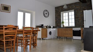 Eine geräumige Küche mit Waschmaschine, Holzstühlen und einer großen Uhr an der Wand.