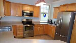 A kitchen with wooden cabinets, a stainless steel refrigerator, a microwave, and an oven.