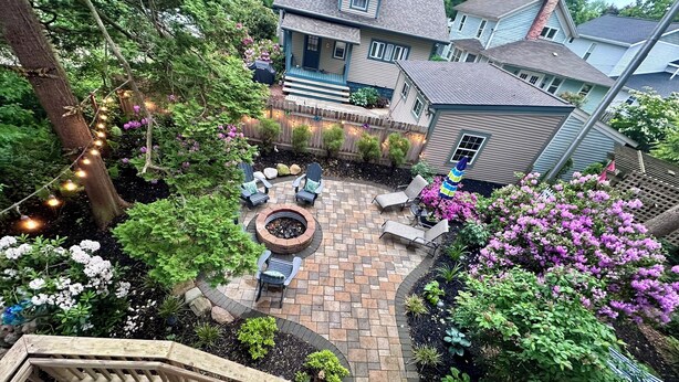 A backyard with a fire pit, outdoor seating, and a wooden deck.