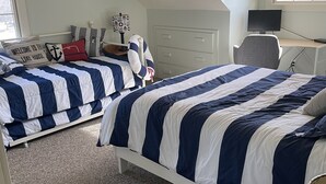 A bedroom with two beds, a desk, a chair, and a TV.