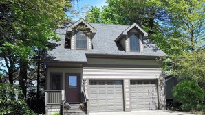A two-story house with a gabled roof, a front porch, and two garage doors.