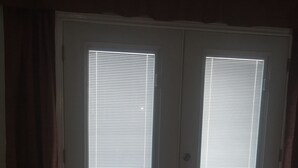A room with a closed door, a bench, and a rug on the floor. - Kwik Kabana "Where the Beach Counts" (Galveston)