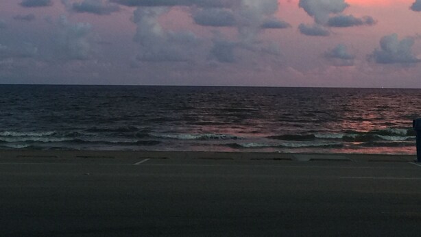 A beach with a view of the ocean and a sunset sky with clouds. - Kwik Kabana "Where the Beach Counts" (Galveston)