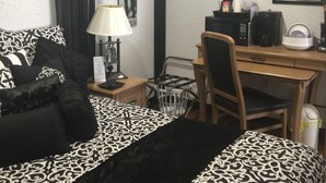 A hotel room with a bed, a desk, a chair, a lamp, and a framed picture on the wall. - Kwik Kabana "Where the Beach Counts" (Galveston)