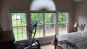 A bedroom with a treadmill, large windows, a bed, and a lamp. - Great waterfront relaxation! (Bumpass)
