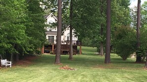 A house with a deck, surrounded by trees and a well-maintained lawn. - Great waterfront relaxation! (Bumpass)