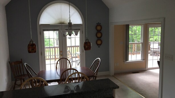 A dining area with a table and chairs, a large arched window, and a view of the outdoors. - Great waterfront relaxation! (Bumpass)