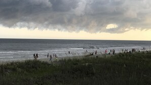 A beach with people walking along the shore and a cloudy sky above. - 2 BR, 2 Bath, Oceanfront-First Floor-Condo A6-Dog Friendly-Wifi - NO-SMOKING! (North Myrtle Beach)