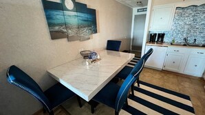A dining area with a marble table, blue upholstered chairs, a striped rug, and a wall-mounted artwork depicting a beach scene. - 2 BR, 2 Bath, Oceanfront-First Floor-Condo A6-Dog Friendly-Wifi - NO-SMOKING! (North Myrtle Beach)